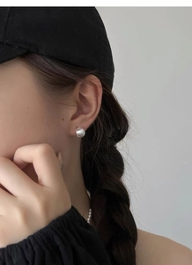 Gros plan de boucles d'oreilles arc en argent S999 mat brossé sur un modèle élégant