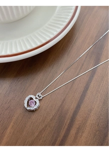 Detail shot of heart pendant necklace with pink gemstone on wooden background