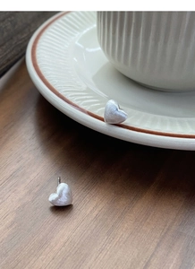 Détail de boucles d'oreilles en argent en forme de cœur avec une texture brossée mate
