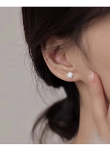 Close-up of S925 sterling silver camellia flower stud earrings worn on a female ear