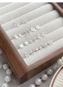 Detailed view of S999 silver stud earrings collection in a luxury wooden jewelry box