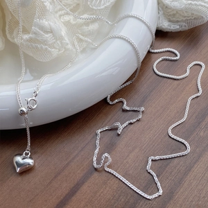 Minimalist S925 sterling silver heart necklace with adjustable sliding chain on a ceramic plate