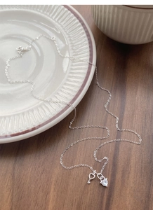 Detailed view of S925 silver heart key pendant necklace with clear zircon on a ceramic dish