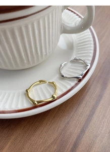 Detailed close-up of gold and silver twig-textured open rings on a white ceramic saucer