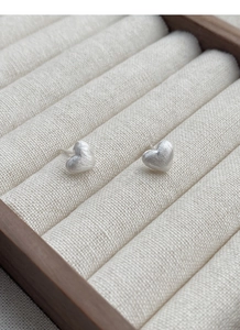 Gros plan sur des boucles d'oreilles cœur en argent mat avec texture brossée