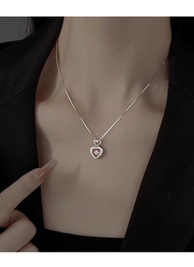 Close-up of S925 sterling silver heart necklace with pink gemstone on female model