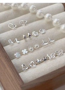 Macro shot of assorted S999 silver heart and floral stud earrings in a jewelry box
