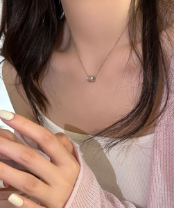 Detail of S925 sterling silver cylinder pendant necklace on model with soft lighting
