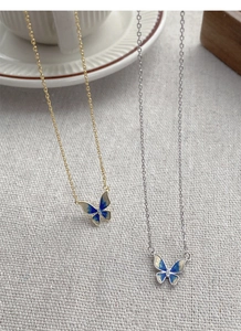 Close-up of S925 silver and gold butterfly necklaces with blue enamel and crystals