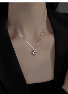 Detail of S925 silver necklace featuring a sparkling pink heart pendant on model's neck