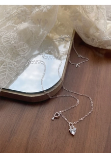 Detail of silver S925 heart and crystal key pendant necklace on lace background