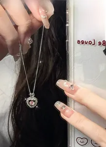 Detail of a pink heart gemstone pendant with silver-toned chain held in hand