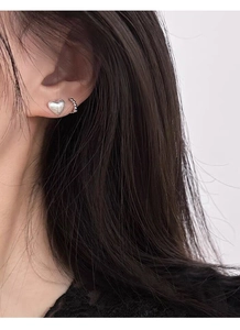Détail d'une boucle d'oreille cœur en argent S999 mat et d'un ear cuff sur un mannequin