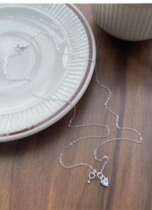 Macro detail of S925 sterling silver heart-cut stone and vintage key pendant necklace