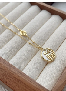 Gros plan du collier en argent S925 doré avec pendentif Fu en nacre blanche en boîte