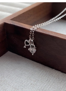 Detail of silver S925 heart lock and key pendants with zircon on a fine chain