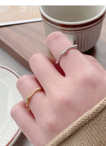 Detail of gold and silver irregular textured rings worn on fingers in a lifestyle setting