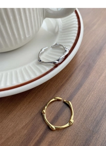 Detailed close-up of gold and silver S925 rings with irregular bamboo texture on dark wood