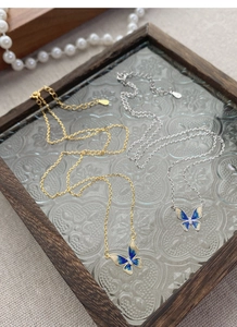 Detail of gold and silver S925 enamel butterfly necklaces with blue gradient wings