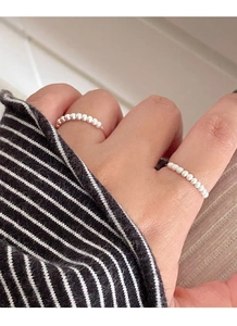 Detailed macro view of two minimalist S925 sterling silver rings with tiny white pearls