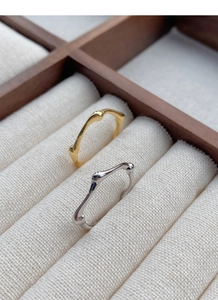 Macro shot of gold and silver irregular textured stackable rings on rustic display tray