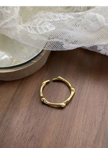 Macro detail of a golden bamboo style open ring on a delicate white lace background