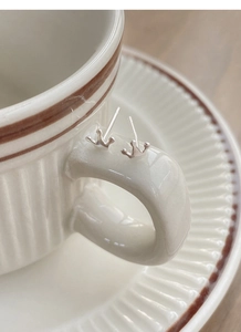 Detailed close-up of S999 sterling silver crown stud earrings on a vintage cup