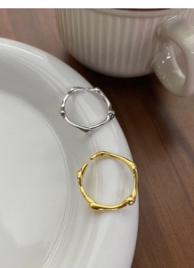 Detailed view of gold and silver irregular textured open rings on a ceramic plate
