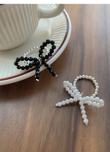Detail of handcrafted elastic beaded rings with black crystal and pearl bow designs