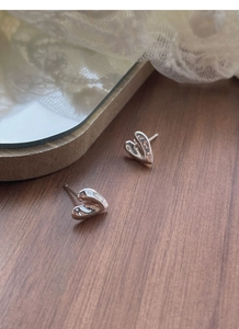 Detail of S999 sterling silver heart stud earrings with fluid texture on dark wood background