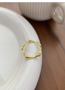 Detail of a minimalist gold irregular textured ring on a white ceramic plate