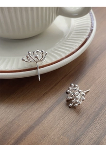 Detailed close-up of S925 sterling silver firework stud earrings on a vintage cup rim