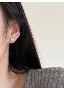 Close-up of heart-shaped S999 sterling silver stud earrings on a model with a mirror finish