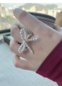 Detail of S925 silver stretch ring with white pearl bow design worn on finger