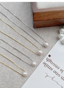 Detailed view of S925 silver and gold pearl necklaces on a rustic linen background