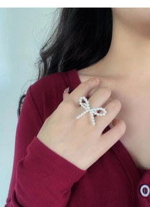 Detail of handmade elastic pearl ring with butterfly bow on a female model finger