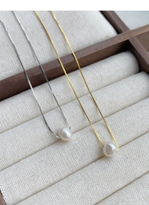 Macro shot of gold and silver S925 sterling silver necklaces with single white pearls