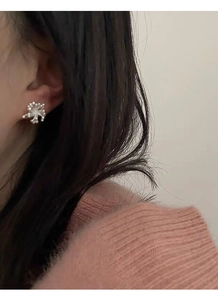 Close-up of elegant silver floral stud earring worn by a model in a warm setting