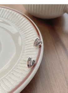 Macro shot of S999 sterling silver heart stud earrings with unique lava texture on a plate