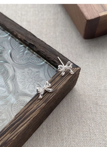 Gros plan détaillé des boucles d'oreilles nœud en argent S999 avec finition miroir polie