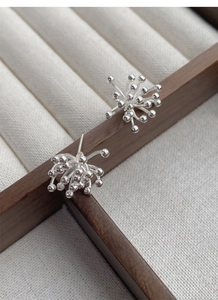 Detailed view of S925 sterling silver fireworks stud earrings on a wooden jewelry box