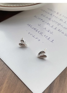 Close-up of S999 sterling silver heart stud earrings with unique lava texture on a card