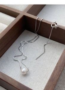 Detailed view of single freshwater pearl pendant on a silver box chain in a jewelry tray