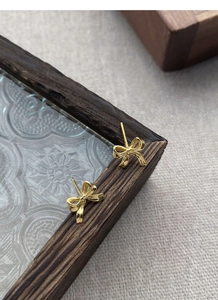 Vue détaillée de boucles d'oreilles nœud doré avec finition polie et rubans