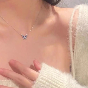 Elegant S925 silver blue enamel butterfly necklace worn by a model in a cozy white sweater