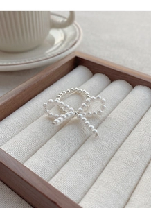 Detail of S925 silver beaded ring with pearl bow design on white velvet display case