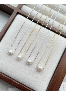 Detail of four S925 silver and gold box chains with lustrous white freshwater pearls