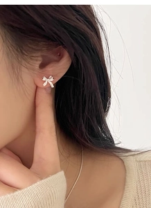 Gros plan d'élégantes boucles d'oreilles nœud en argent S999 portées par un mannequin