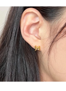 Gros plan sur une boucle d'oreille nœud dorée en argent S999 avec un design de ruban