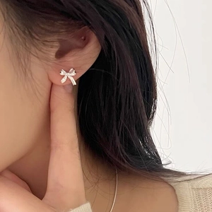Élégantes boucles d'oreilles nœud papillon en argent fin S999 portées par un modèle